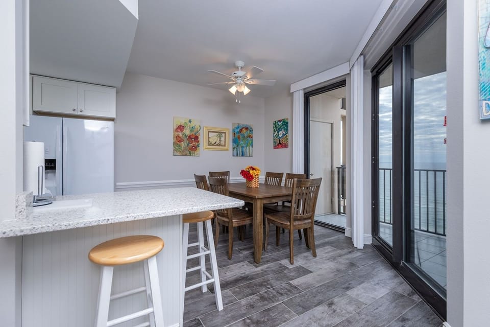 Gather around the wooden dining table, surrounded by colorful artwork and enjoying refreshing breezes from the balcony