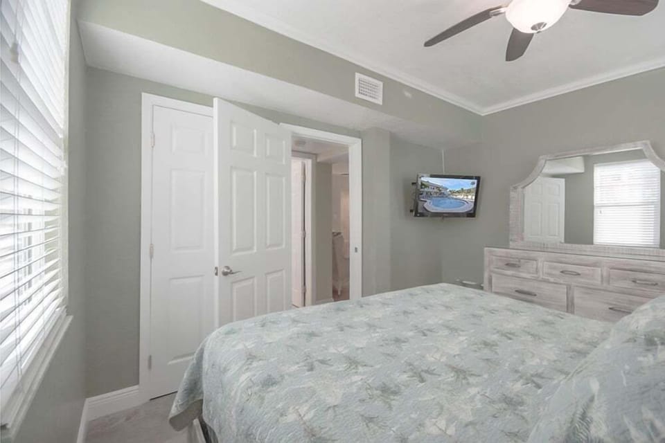 Bedroom features a plush king sized bed, tv, vanity mirror, and ceiling fan. Perfect for a serene and cozy sleep.