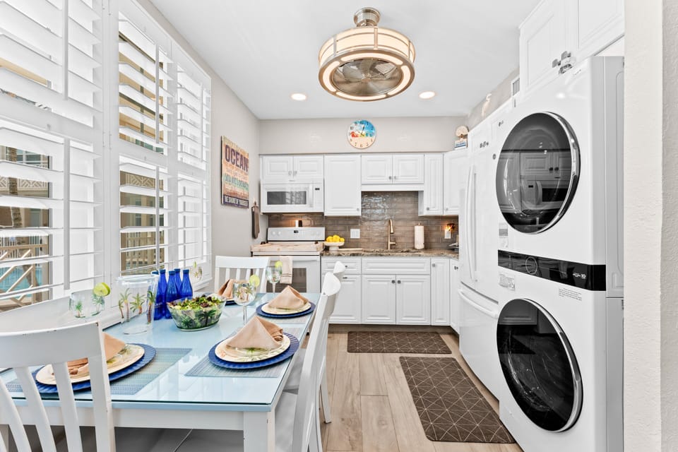 Enjoy home-cooked meals at the bright dining table just steps from the fully stocked kitchen, complete with a stacked washer/dryer for ultimate convenience.