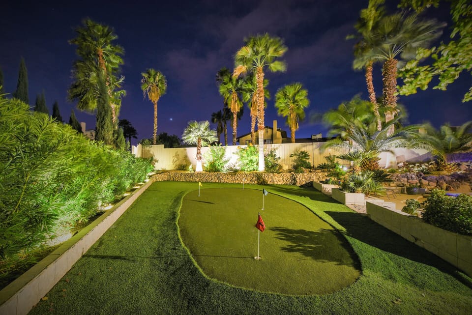 Large 4-hole putting green with bright landscape lighting tropical oasis 