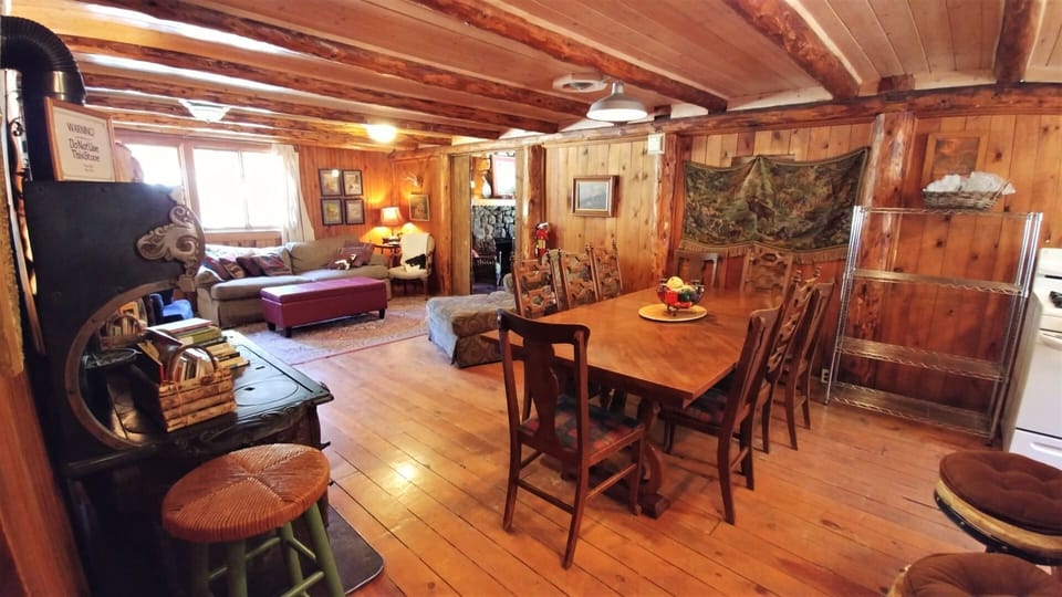 Step into your cozy rustic retreat where warm wood envelops you, a spacious dining table invites family meals, and the living area beckons for relaxation after mountain adventures.