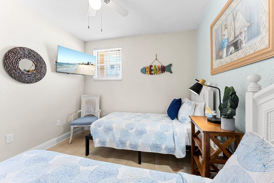 Our Guest Bedroom features 2 single beds, a smart TV, and a ceiling fan.