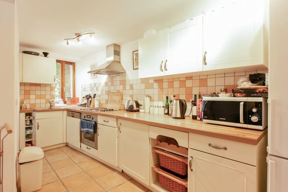 A well equipped kitchen with all necessary appliances including two fridges, oven, hob, and microwave with access to the courtyard