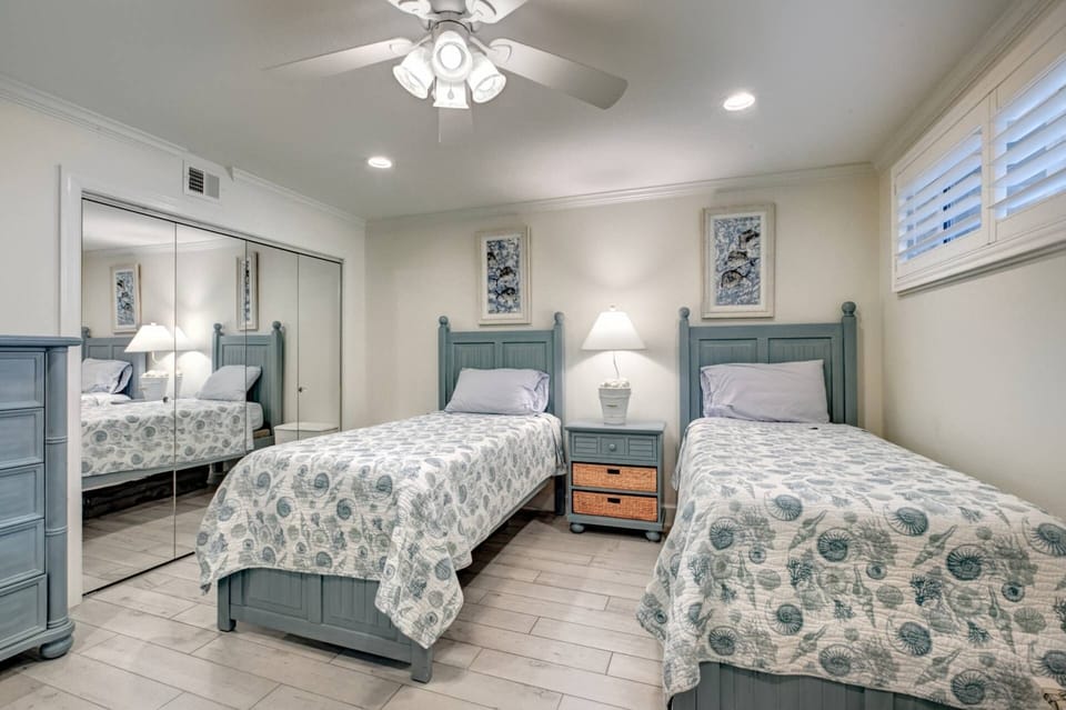 Guest bedroom with twin beds and his/hers mirrored closets.