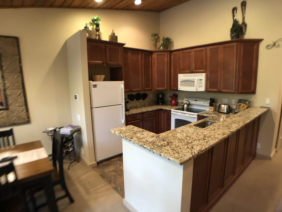 Kitchen includes electric range, refrigerator, microwave and 2 coffeemakers.
