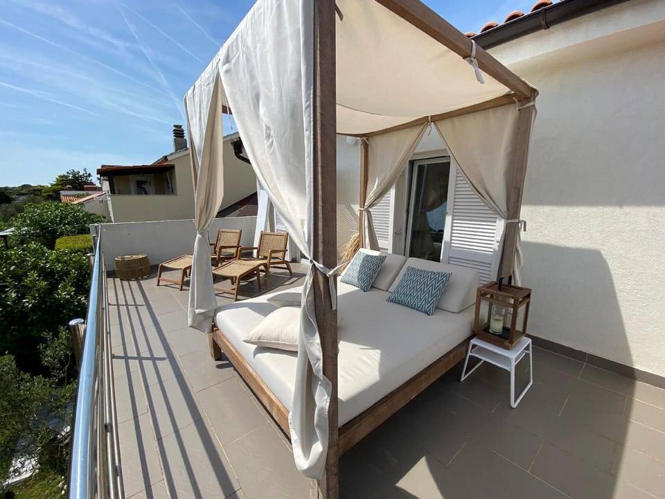 Canopy bed and teak loungers  on the upper terrace