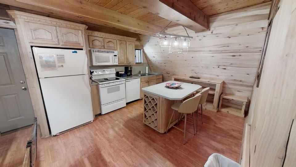 Your fully equipped kitchen invites you to cook together under vaulted wood ceilings, with a cozy breakfast island for morning coffee or evening snacks in this charming cabin retreat.