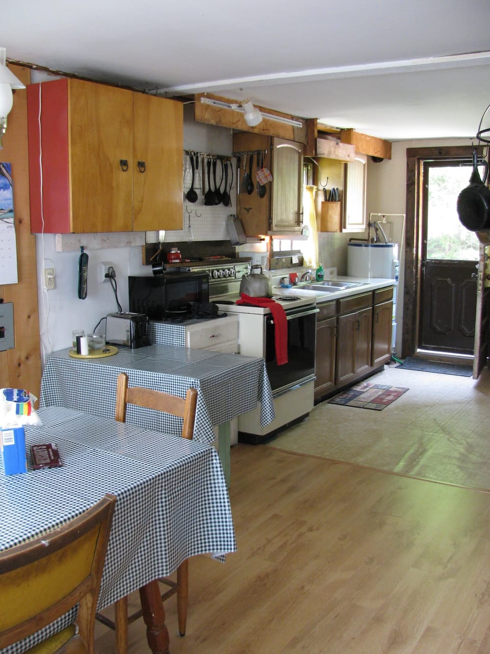 Kitchen with electric range, microwave, refrigerator and cooking gear.
