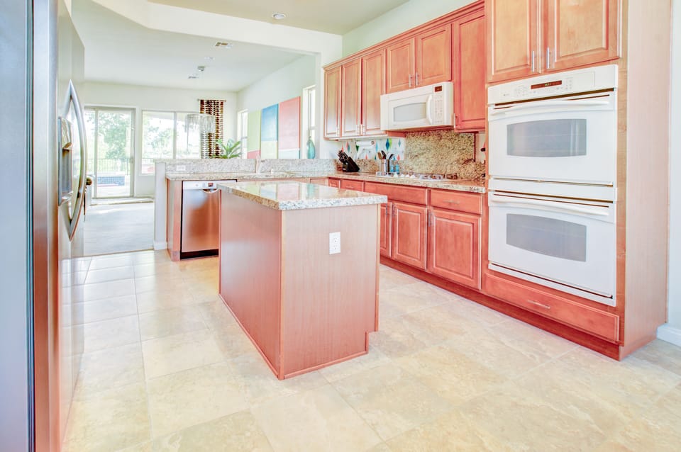 Island kitchen with double ovens, gas range and built in microwave. 