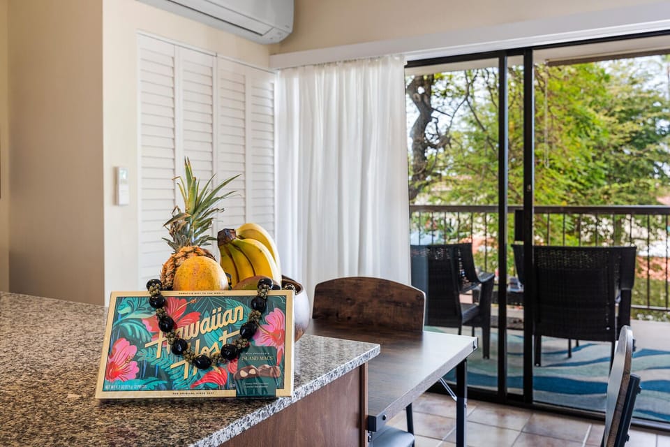 Your kitchen overlooks lush greenery through floor-to-ceiling windows, creating a bright, airy space for preparing tropical treats.