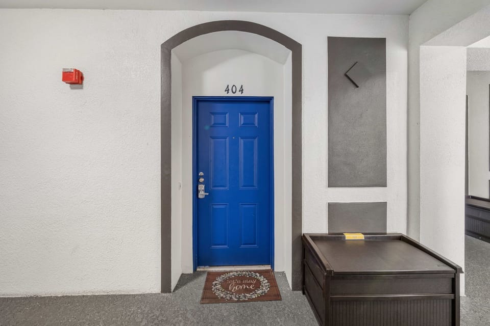 Welcome to Apt 404! A cheerful blue door, arched entry, and smart lock make self check-in simple and stylish.