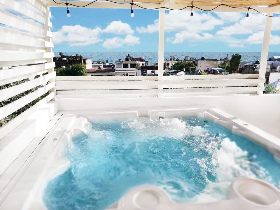 Exciting hot tub on rooftop terrace, with ocean view, next to outdoors shower.