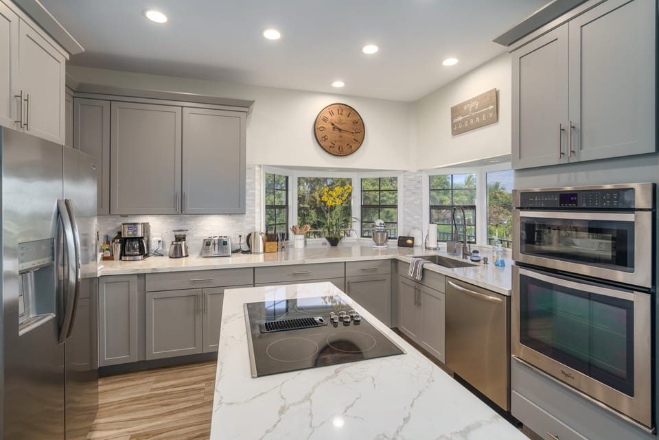 A sleek, modern kitchen with a spacious island, stainless steel appliances, and a cozy dining area. Perfect for preparing meals while enjoying the tropical scenery.