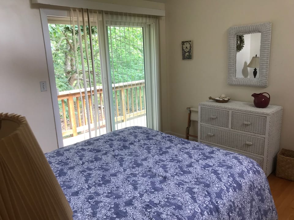 View from queen bed to balcony. Dresser and closet for storage. Hard-wood floors