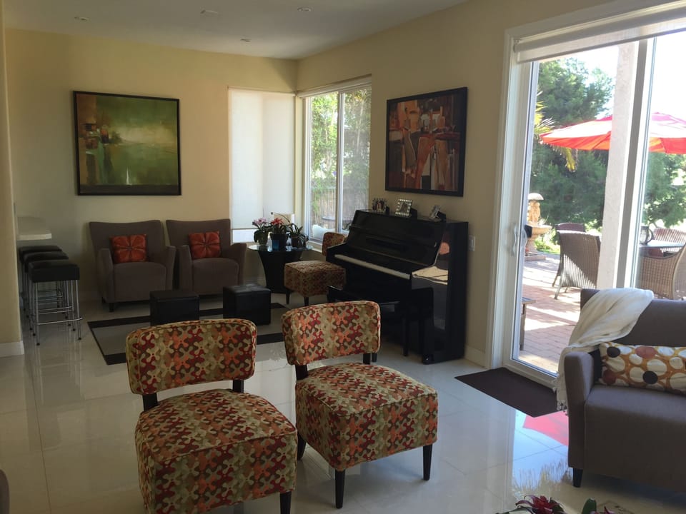 Piano and conversation area behind living room. 3 Bar Stools face open kitchen.