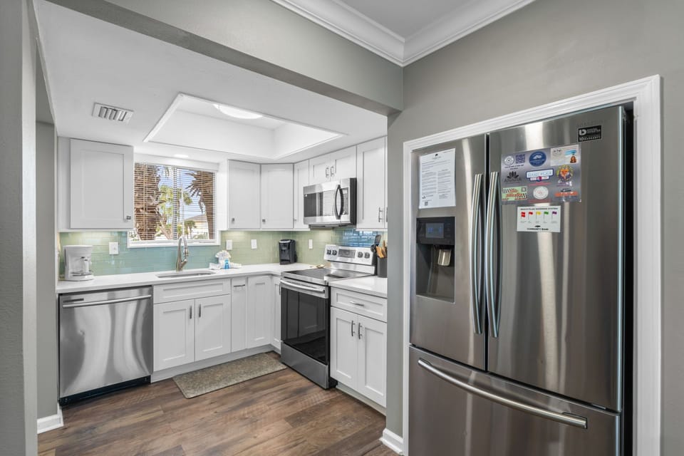 Your modern kitchen features stainless steel appliances, crisp white cabinetry, and a serene mint backsplash perfect for home-cooked meals.