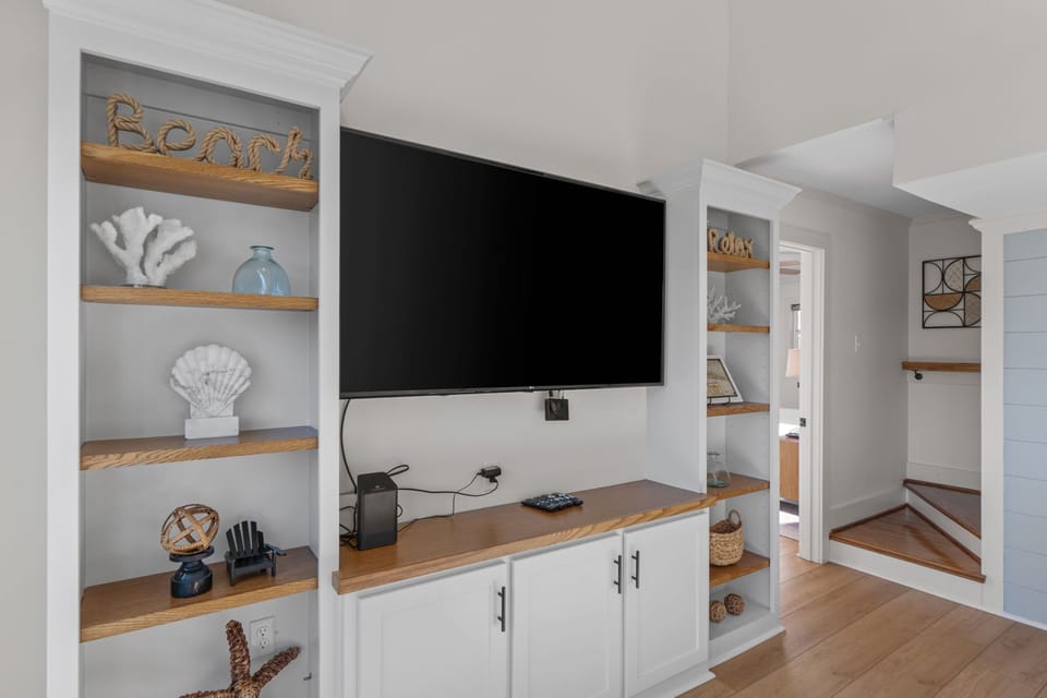 Unwind in your stylish living space with coastal charm and modern entertainment center perfectly integrated into custom shelving.