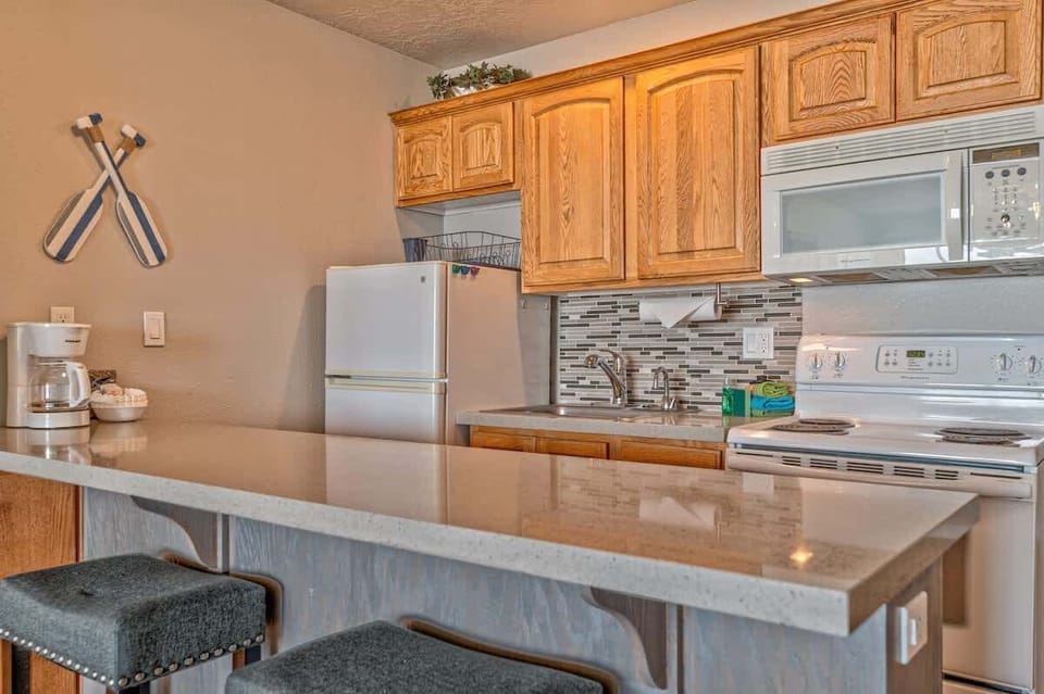 The kitchen includes a full-range oven, cooktop, fridge, and microwave