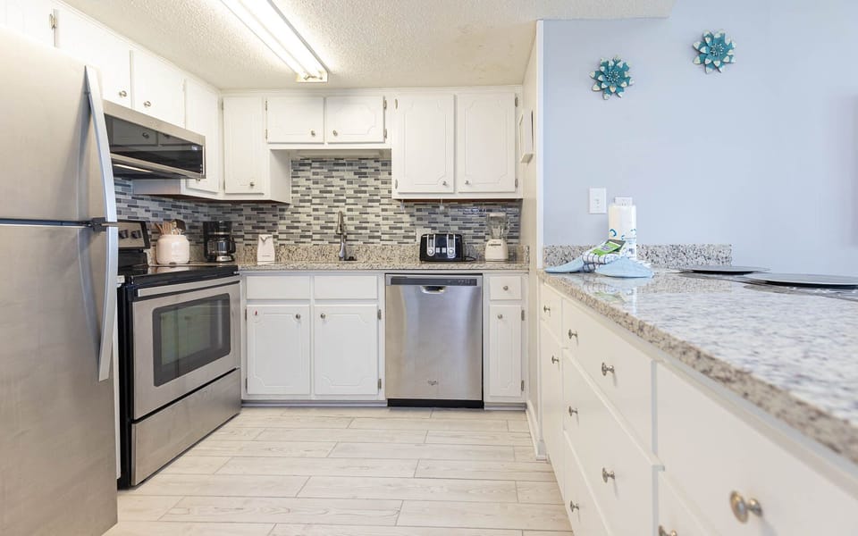 The kitchen features stainless appliances, granite countertops, and cheerful coastal decor for a delightful experience
