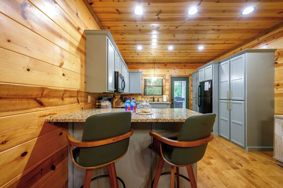Gather around your fully equipped kitchen where warm wood tones meet modern convenience. Granite counters, stainless appliances, and cozy seating invite you to savor morning coffee or prepare family meals together.