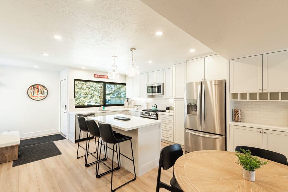 modern kitchen features white shaker cabinets, quartz countertops, stainless steel appliances, and a spacious island with seating.