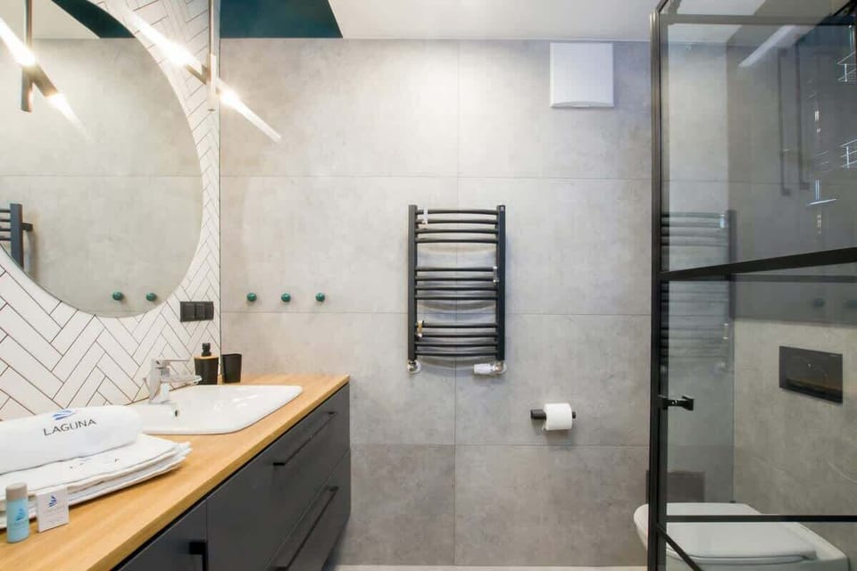 Another angle of a bathroom with a glass shower, minimalist design, and wood-accented vanity, blending style with functionality.