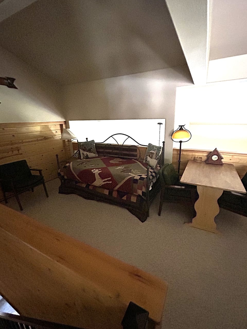 Your cozy attic bedroom features rustic wood beams, charming sloped ceilings, and warm bedside lighting for peaceful nights.