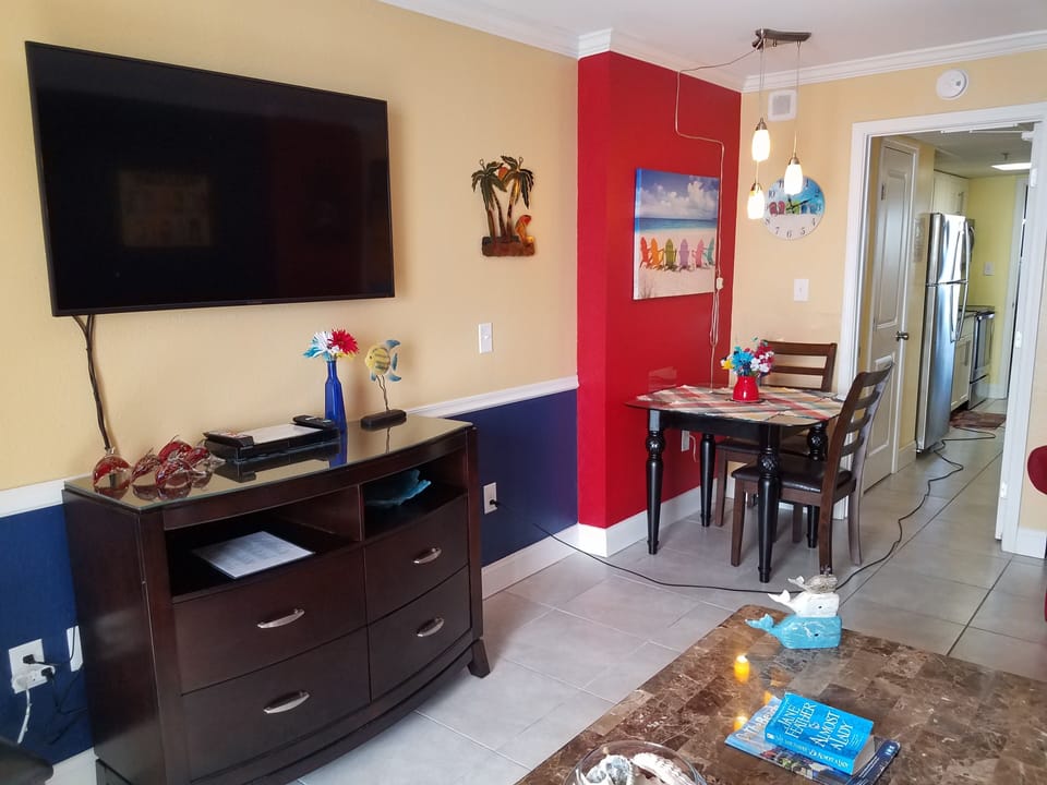 Living room area, 50 inch TV, glass dinette & entryway to kitchen (background.