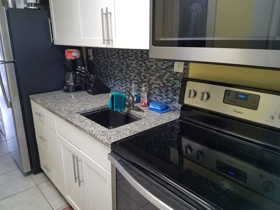 Another view of kitchen smooth top electric stove,  ice maker refrigerator