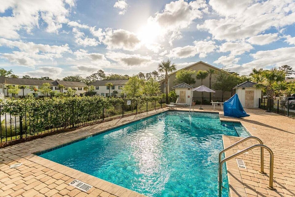 Community pool area with iron fencing and umbrella