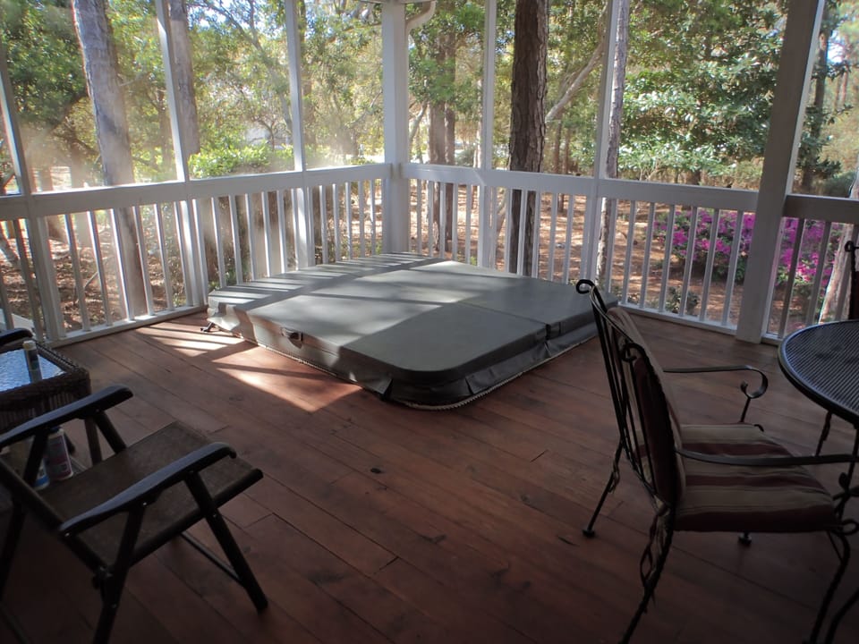 Screened-in porch with hot tub, outdoor dining, and gas grill