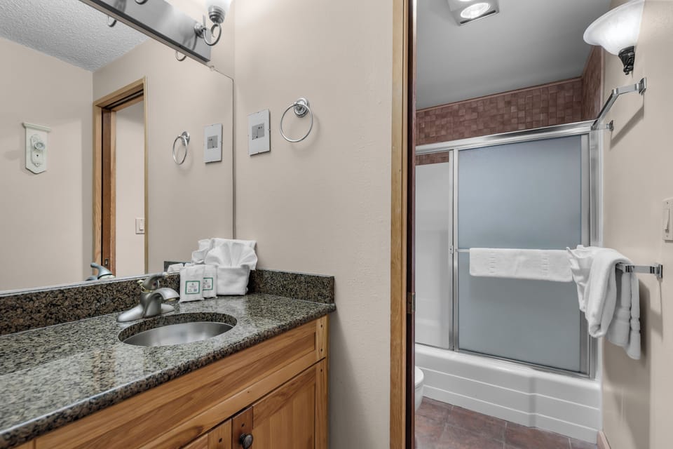Step into your bathroom with granite countertops, warm wood cabinetry, and a well-lit vanity. The separate tub and shower offer flexibility for your morning routine or evening wind-down.