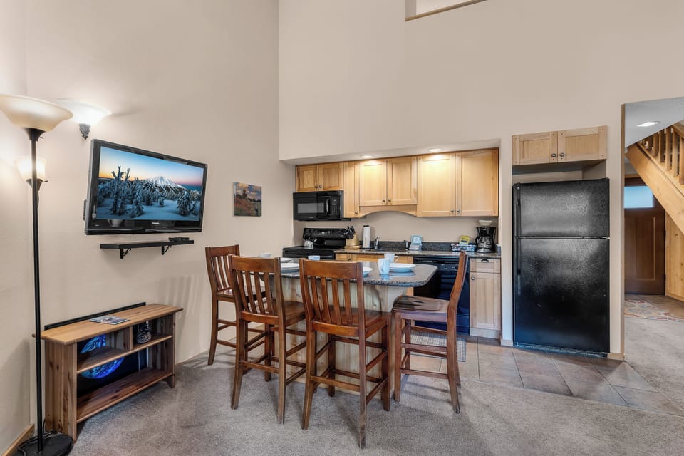 Your cozy open-concept retreat features a fully equipped kitchenette and casual dining space, perfect for relaxing après-ski meals together.