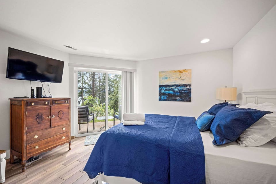 Unwind in your tranquil bedroom featuring crisp blue linens, warm wood furnishings, and sliding doors to your private outdoor space.