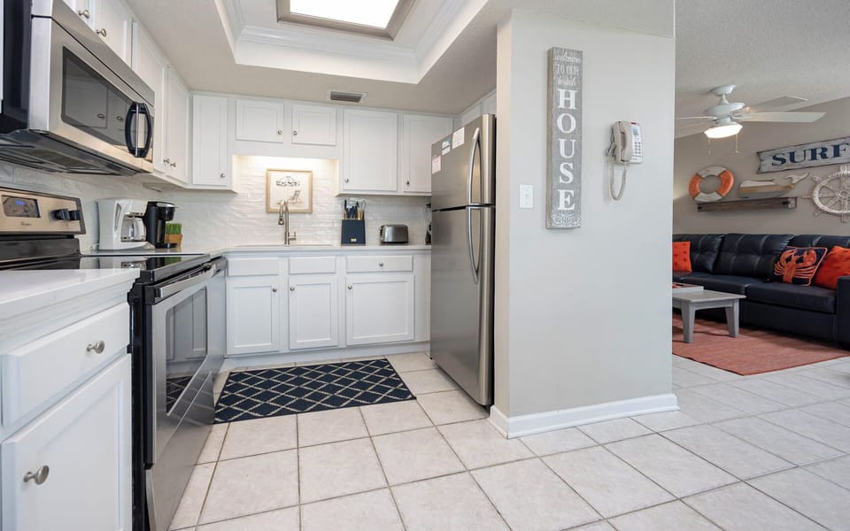 The modern kitchen features stainless appliances, Keurig and coffee maker, and a bright, airy design with white cabinetry