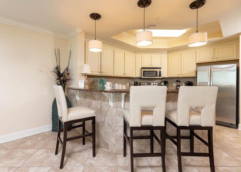 The kitchen features light cabinetry, granite countertops, and stainless appliances, perfect for casual dining at the bar
