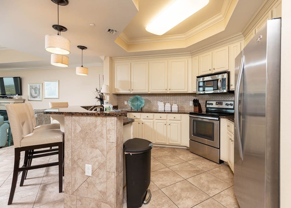 This modern kitchen features stainless appliances, granite countertops, and a cozy bar area for casual dining