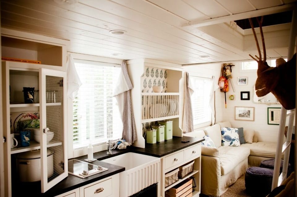 Kitchenette with view into living area. Small refrigerator and stovetop. 