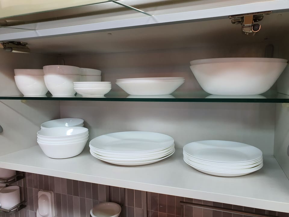 Bowls and plates in glass cabinet above sink