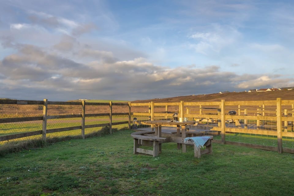 Garden lawn with bench at By The Beach coastal home Cornwall