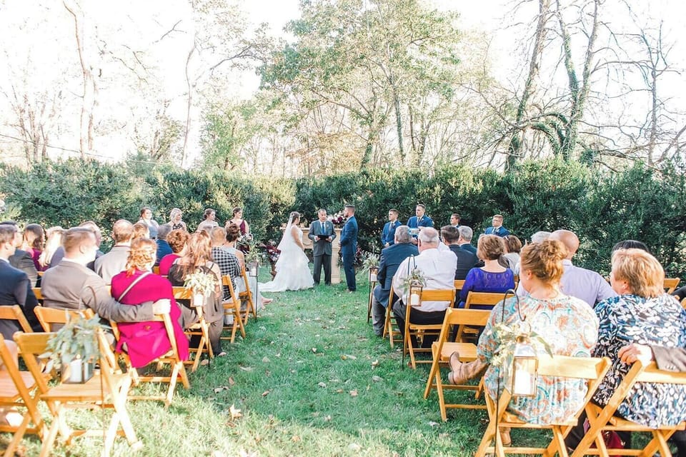 Ceremony on front lawn surrounded by Boxwood bushes.