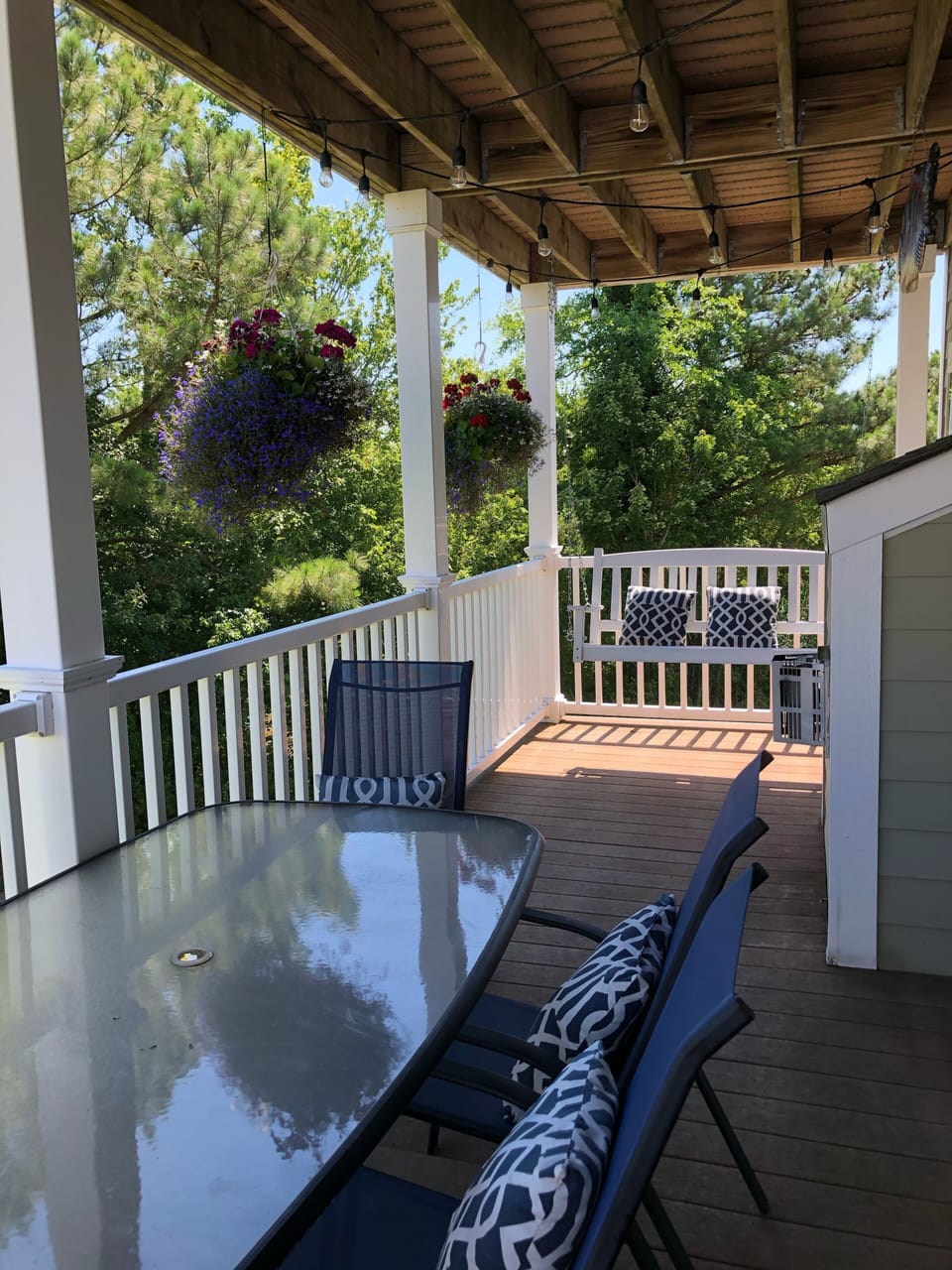 Main floor deck with string lights, porch swing, outdoor dining set. 