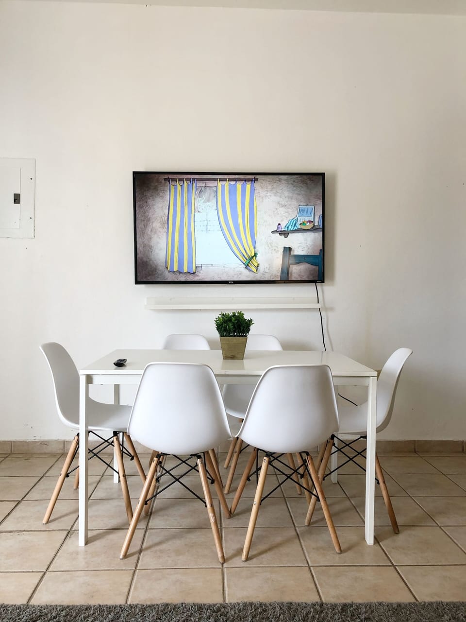 Area de comedor con 6 sillas, smart TV y esta proximo al area de cocina.