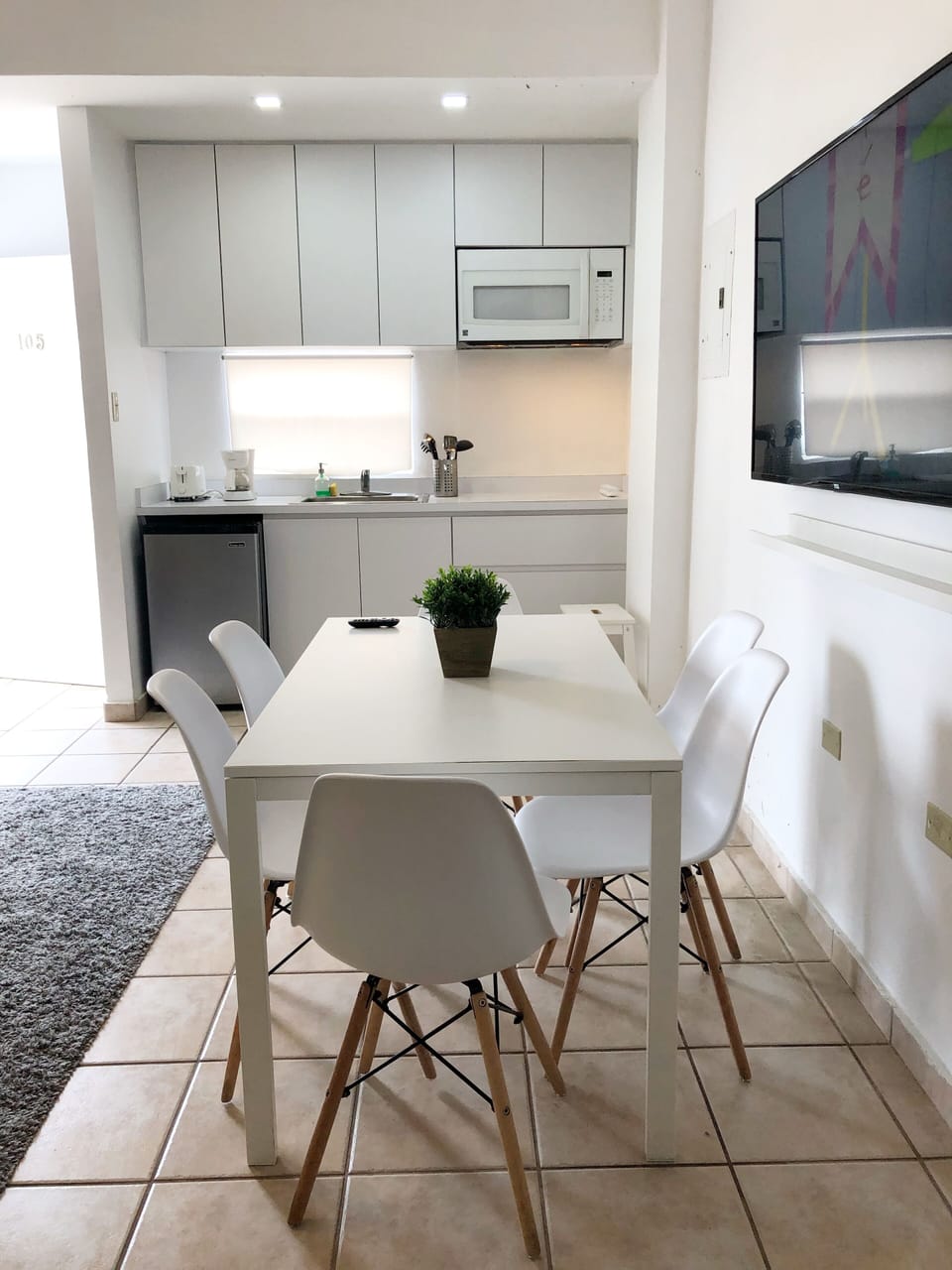 Area de comedor con 6 sillas, smart TV y esta proximo al area de cocina.