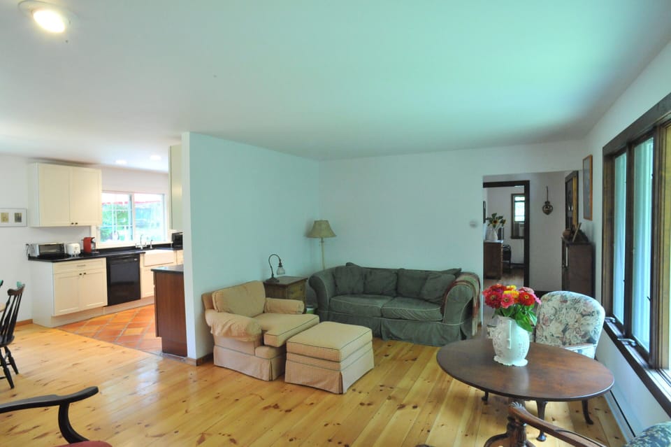 Living room area with partial view of kitchen- wide-plank pine floors