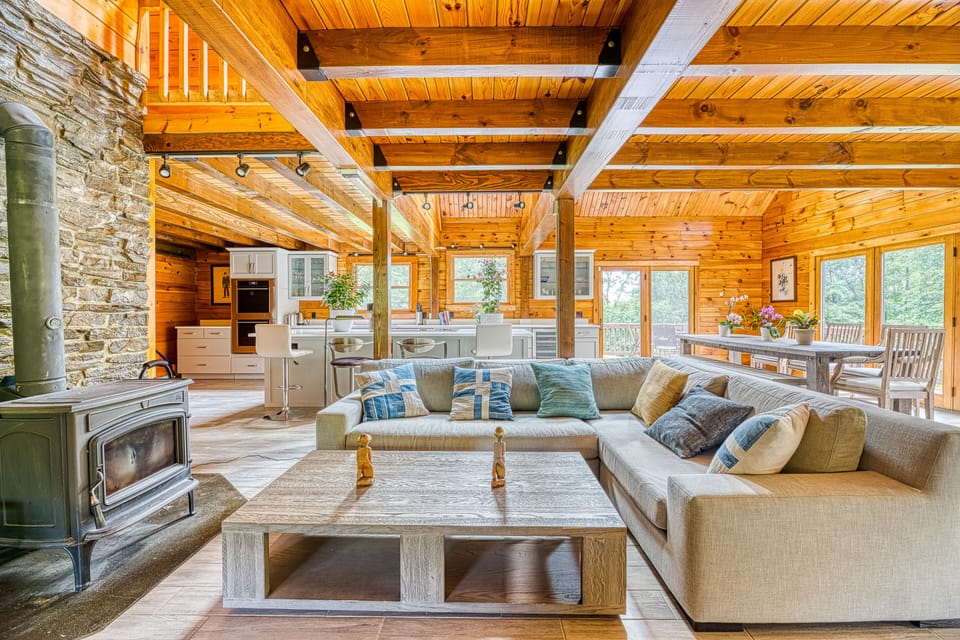 View of the wood-burning stove, sectional sofa, kitchen and dining area