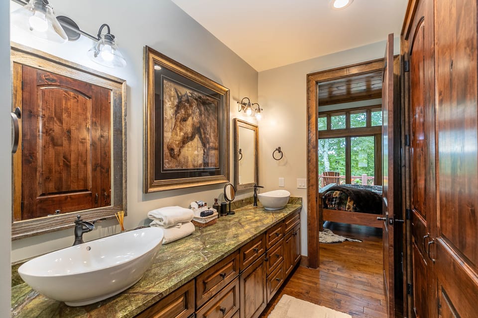 The master bath at Prancing Horse Lodge At Eagles Nest feels like a gallery, with vessel sinks and rich wood details throughout.