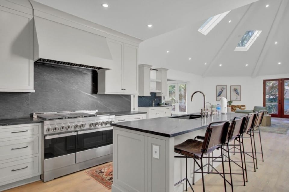 - Cook like a pro with a gas range, double ovens, and sleek black backsplash - Stylish island offers prep space, bar seating, and modern pendant lighting - Skylights and vaulted ceilings flood the space with natural light