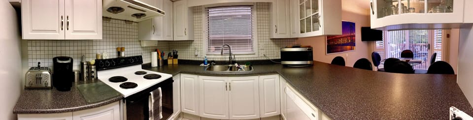 Bright open-concept fully equipped kitchen looking onto dining area.