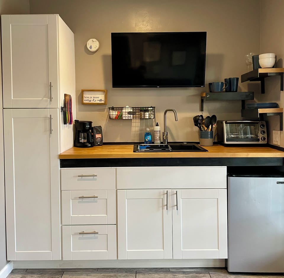 Kitchenette with hot plate, mini fridge, toaster oven and cooking utensils. 